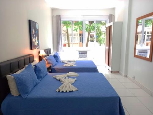 3 Betten in einem Zimmer mit blauer Bettwäsche in der Unterkunft TC308 Studio na Praia - Espaçoso e aconchegante in Rio de Janeiro