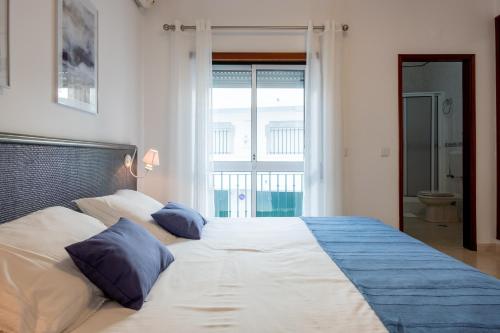 a bedroom with a large bed with blue pillows at T1 em Altura in Altura