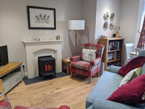 a living room with a fireplace and a couch and chair at Kinloch Rannoch Holiday Cottage in Kinloch Rannoch