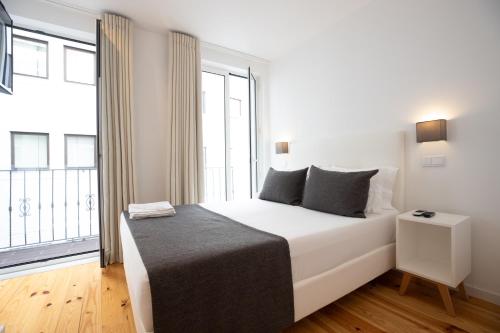 Un dormitorio con una cama blanca con una ventana grande. en Mystay Porto Batalha, en Oporto