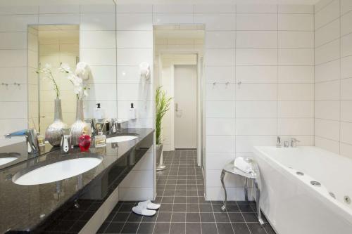 uma casa de banho branca com 2 lavatórios, uma banheira e um tubermott em Thon Partner Elgstua Hotel em Elverum
