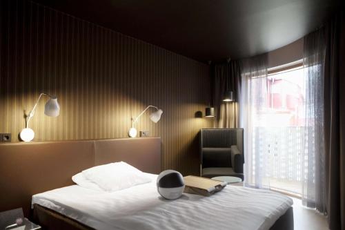 Un dormitorio con una cama y una ventana con un libro. en Scandic Paasi, en Helsinki