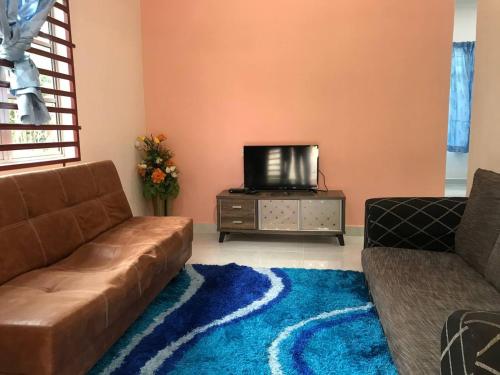ein Wohnzimmer mit einem Sofa und einem TV in der Unterkunft Tok Chik Homestay in Sik