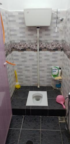 a bathroom with a toilet in a tiled floor at Tok Chik Homestay in Sik
