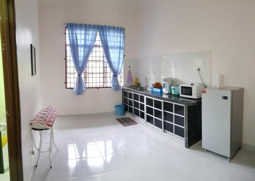uma cozinha com um frigorífico e uma mesa com um micro-ondas em Tok Chik Homestay em Sik