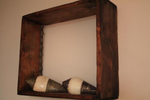 a wooden mirror with three wine corks on a wall at B&B Sa Serra in Stintino
