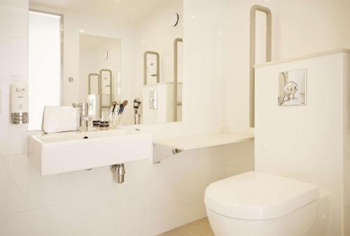 a white bathroom with a toilet and a sink at Scandic Haugesund in Haugesund
