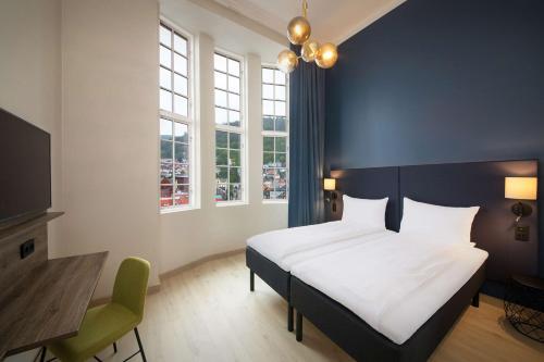 a bedroom with a bed and a desk and windows at Scandic Torget Bergen in Bergen