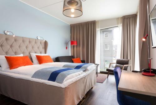 1 dormitorio con 1 cama con almohadas de color naranja y azul en Scandic Stavanger City en Stavanger