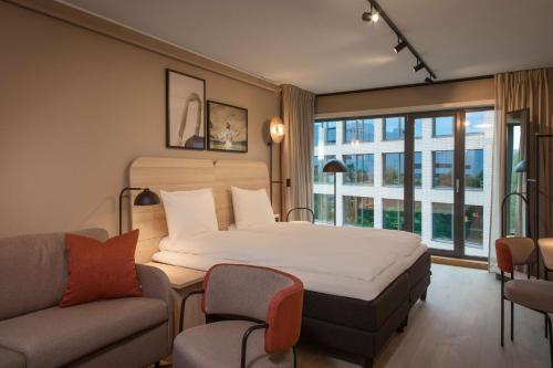 - une chambre avec un grand lit et un canapé dans l'établissement Scandic Helsfyr, à Oslo