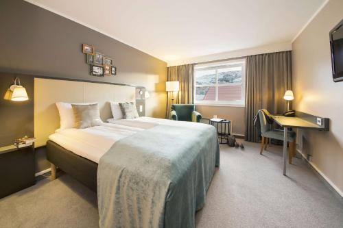 ホニングスヴォーグにあるスカンディック ブリッゲンの大きなベッドとデスクが備わるホテルルームです。