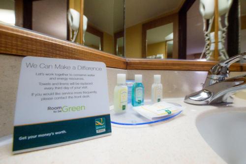 a bathroom sink with a sign in front of a mirror at Quality Inn Colorado Springs South in Colorado Springs