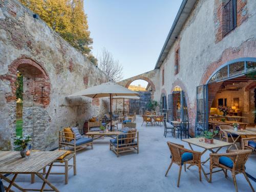 an outdoor patio with tables and chairs and an umbrella at La Pescaia Resort in La Pescaia