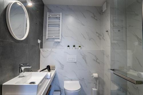 a bathroom with a sink and a toilet and a mirror at Stylchyn 90 Apartamenty nad Jeziorem Czorsztyńskim in Kluszkowce