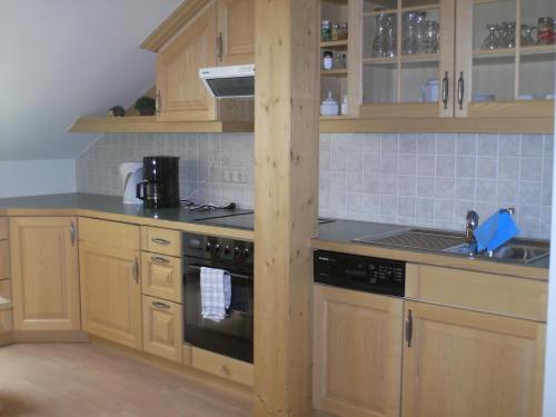 a kitchen with wooden cabinets and a stove at Ferienwohnungen Brunner in Fischen