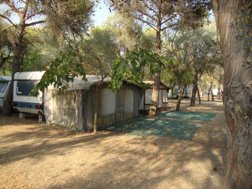a campsite with a camper and a trailer under trees at Camping Tellina in Manfredonia