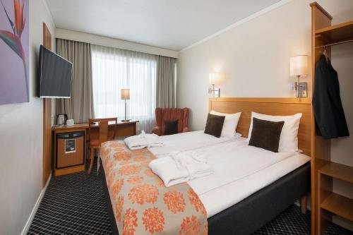 um quarto de hotel com uma cama grande e uma secretária em Scandic Gardermoen em Gardermoen