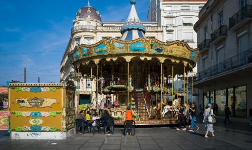 a group of people standing around a carousel in a city at Hôtel Royal in Montpellier
