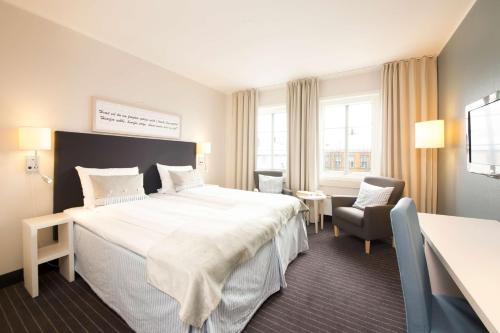 a hotel room with a large bed and a chair at Clarion Collection Hotel Grimstad in Grimstad