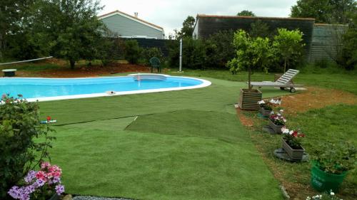 einen Garten mit einem Pool und einer Liegewiese mit Blumen in der Unterkunft LA PASTORALE in Beurlay