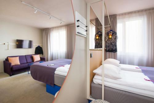 a hotel room with two beds and a couch at Scandic Karl Johan in Oslo