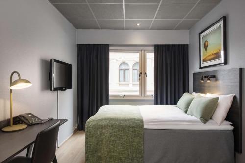 Scandic Ambassadeur Drammen في درّامن: غرفه فندقيه بسرير ومكتب ونافذه