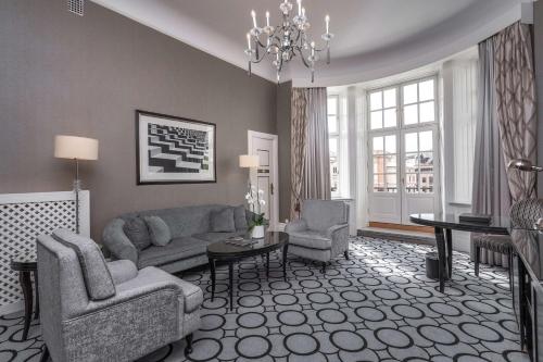 a living room filled with furniture and a large window at Grand Hotel in Oslo