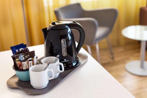 a coffee maker on a tray with cups on a counter at Scandic Meilahti in Helsinki