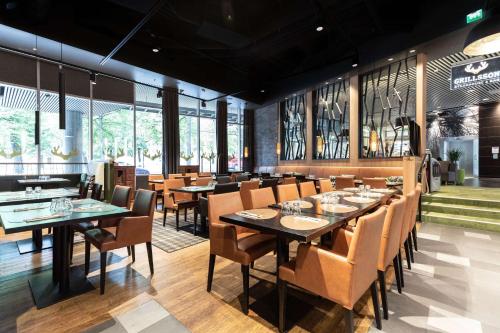a dining room with tables and chairs and windows at Scandic Tampere Hämeenpuisto in Tampere