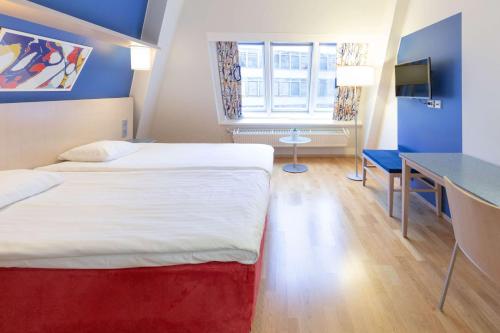 a hotel room with two beds and a desk at Scandic Hakaniemi in Helsinki