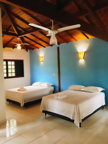 two beds in a room with blue walls and a ceiling at Pousada Azul Banana - Camburi in Camburi