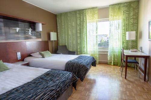 a hotel room with two beds and a desk and a window at Scandic Jyväskylä City in Jyväskylä