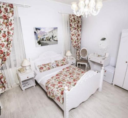 a white bedroom with a bed and a chandelier at The White Hotel Alaçatı in Alaçatı