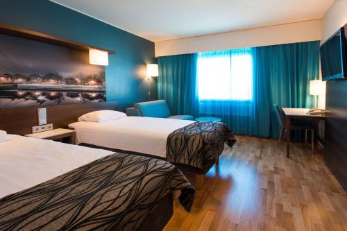 a hotel room with two beds and a desk at Scandic Oulu Station in Oulu