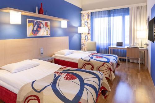 2 Betten in einem Hotelzimmer mit blauen Wänden in der Unterkunft Scandic Hyvinkää in Hyvinkää