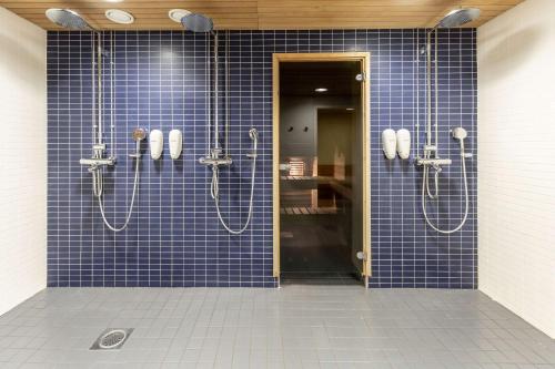 een blauwe betegelde badkamer met 2 douchecabines bij Scandic Hyvinkää in Hyvinkää