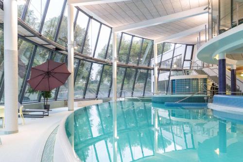 an indoor swimming pool with an umbrella in a building at Scandic Aulanko in Hämeenlinna