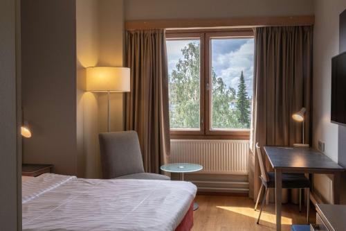 a hotel room with a bed and a desk and a window at Scandic Joensuu in Joensuu