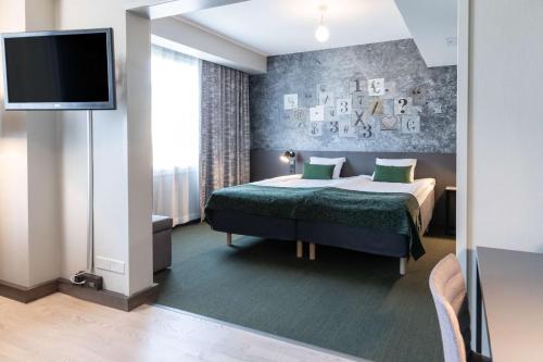 a hotel room with a bed and a flat screen tv at Scandic Kallio in Helsinki