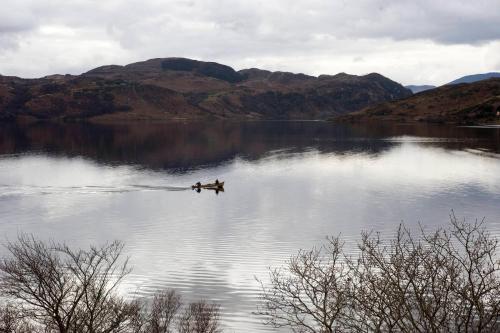 two people are rowing a boat on a lake at Carrig Country House & Restaurant in Killorglin