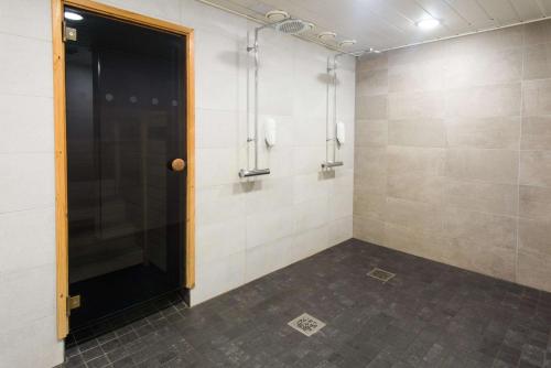 a walk in shower with a black door in a room at Scandic Waskia in Vaasa