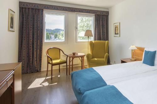 a hotel room with a bed and two chairs and a table at Scandic Hønefoss in Hønefoss