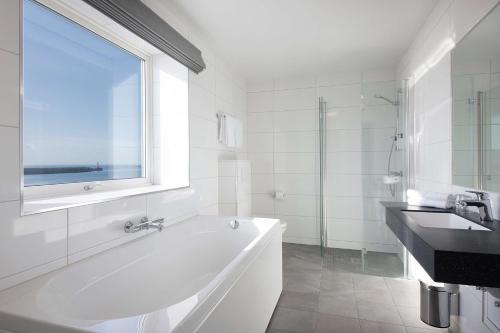 a white bathroom with a tub and a sink at Scandic Vestfjord Lofoten in Svolvær