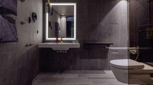 a bathroom with a sink and a toilet and a mirror at Marski by Scandic in Helsinki