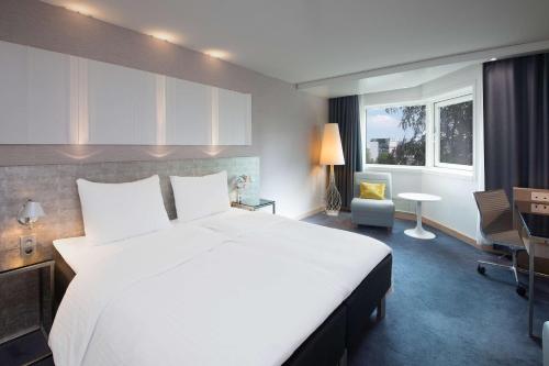 a bedroom with a large white bed and a desk at Scandic Royal Stavanger in Stavanger