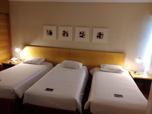 a hotel room with two beds and two nightstands at Golden Tulip Brasília Alvorada in Brasília