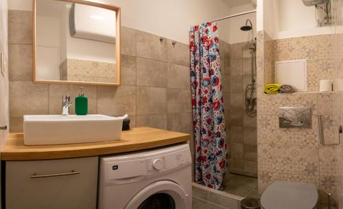 a bathroom with a sink and a washing machine at Helikon 31 Apartman Keszthely in Keszthely