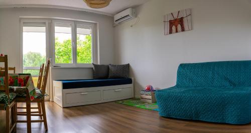 a living room with a blue couch and a chair at Helikon 31 Apartman Keszthely in Keszthely