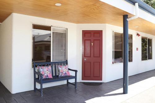 a porch with a red door and a bench at Havelock North Motor Lodge in Havelock North