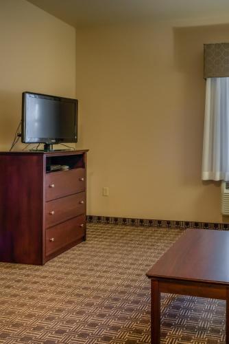 a living room with a flat screen tv on a dresser at MainStay Suites St Robert - Fort Leonard Wood in Saint Robert